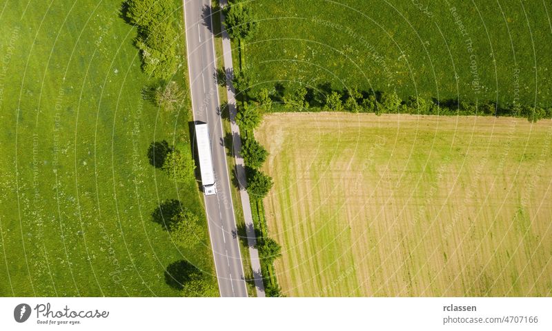 Aerial view of two lane road through countryside and cultivated fields with white truck. Drone shot and copy space for text drone freeway trip aerial view