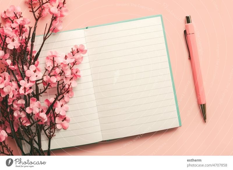 Top view of blank journal open with copy space, pink pen and almond blossoms top view diary textbook reading mock-up closeup paperback concept mock up planner