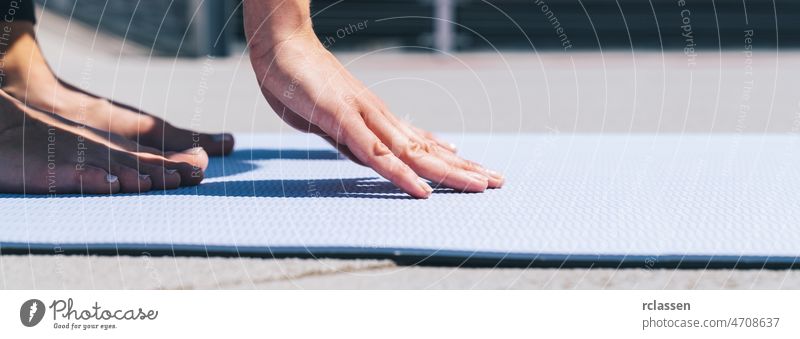 Woman starts stretching workout on a yoga mat outside, with focus on hands. copyspace for your individual text. woman pilates vitality power european concept