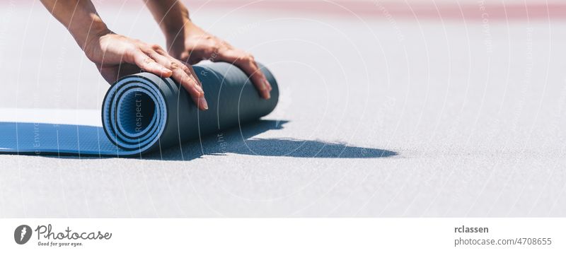 Close-up of a young woman folding blue yoga or fitness mat after working out. keep fit concepts image. copyspace for your individual text. pilates power