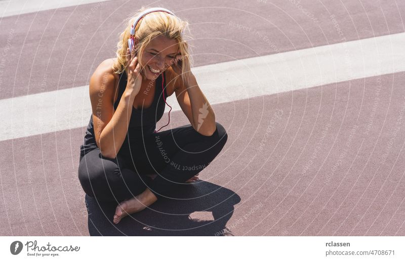 Young woman listening to music with earphones for fitness motivation. Portrait of a smiling young woman in sportswear relaxing sitting getting inspired. copyspace for your individual text.