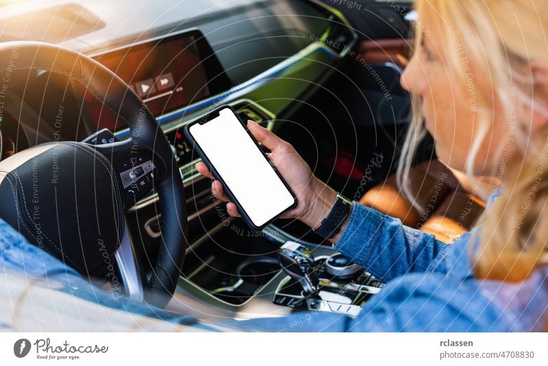 Woman holding black mobile phone in hands with blank desktop screen while car driving at summer in the city, Mockup image drive relax cell application