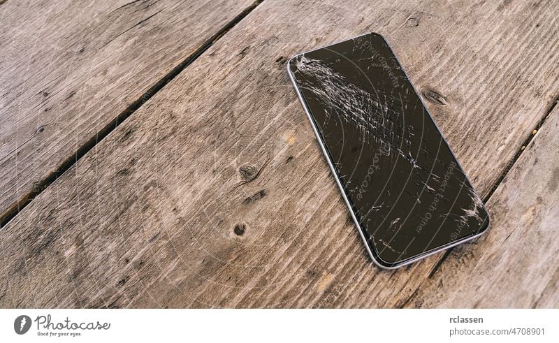 Modern mobile phone with broken screen on wooden background crack smartphone cell scratch smashed cellphone dial accident bad black blue closeup color