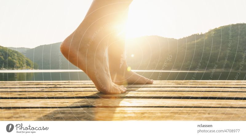 Legs on jetty from a young woman at sunset. yoga concept image barefoot lake feet love lifestyle legs dipping relax swimming bridge copy space wellness pier