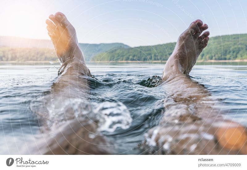 Happy man having fun and splashing water with his feet on a lake happy summer travel chilling nature dip holiday outside pond sea wet swim dipping relax canada