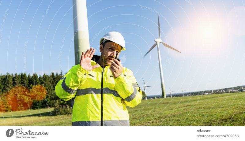 Engineer working a wind turbines, talking on the walkie-talkie for controlling work walky man helmet windmill inspection power communication building