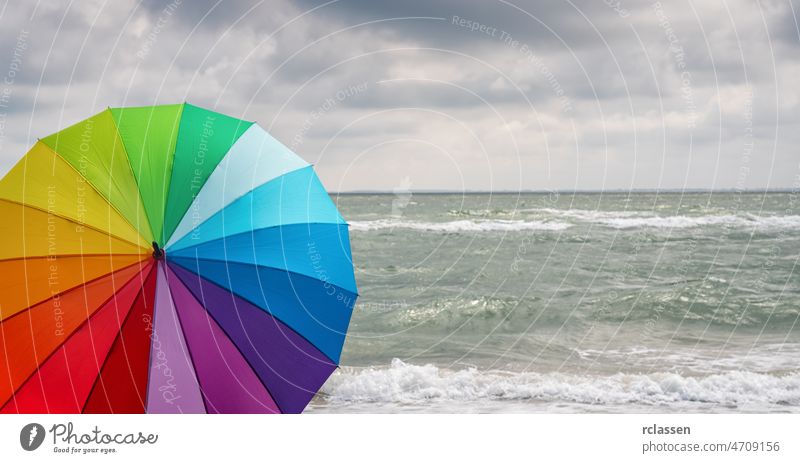 Colorful of umbrella on the beach and foam of sea waves at a thunderstorm, Weather concept image colorful rainbow weather cloud copy space europe news wet
