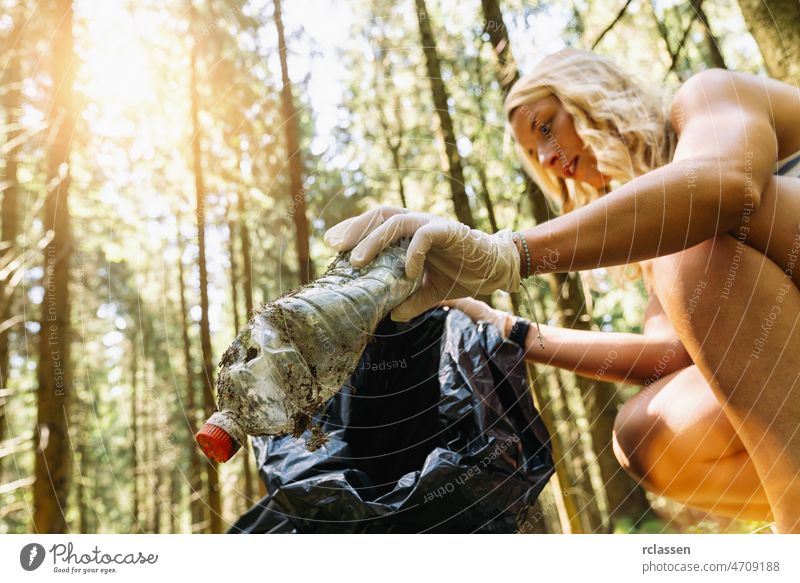 woman picking up a garbage plastic bottle for cleaning the forest, nature and environment cleaning concept image. litter throwing trash people recycling black
