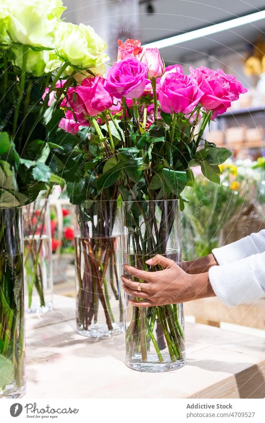 Unrecognizable seller putting vase with roses on table worker floral shop bouquet flower florist plant floristry apron bloom blossom employee professional store