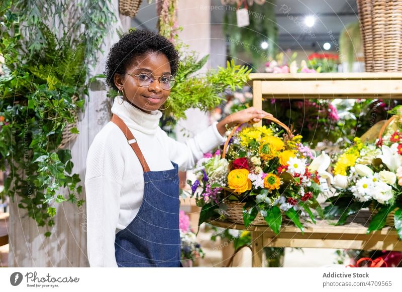 Smiling black woman with bouquet in basket floral shop flower florist work plant floristry industry decorative professional store job female small business