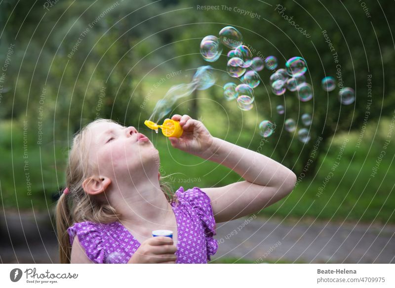 Young girl blowing soap bubbles in the summer greenery Girl Summer Summer dress Joy Playful Green Nature sparkle Happy Infancy Playing Happiness fun Outdoors