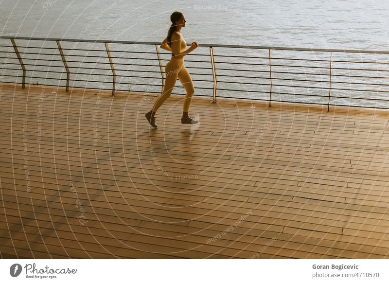 Young woman running on the riverside pier action active activity adult athlete beautiful body bright day exercise exercising female fit fitness healthy