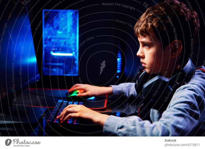 Boy plays computer game at home, gaming addiction gamer workplace boy keyboard virtual entertainment online cybersport equipment streamer male man technology