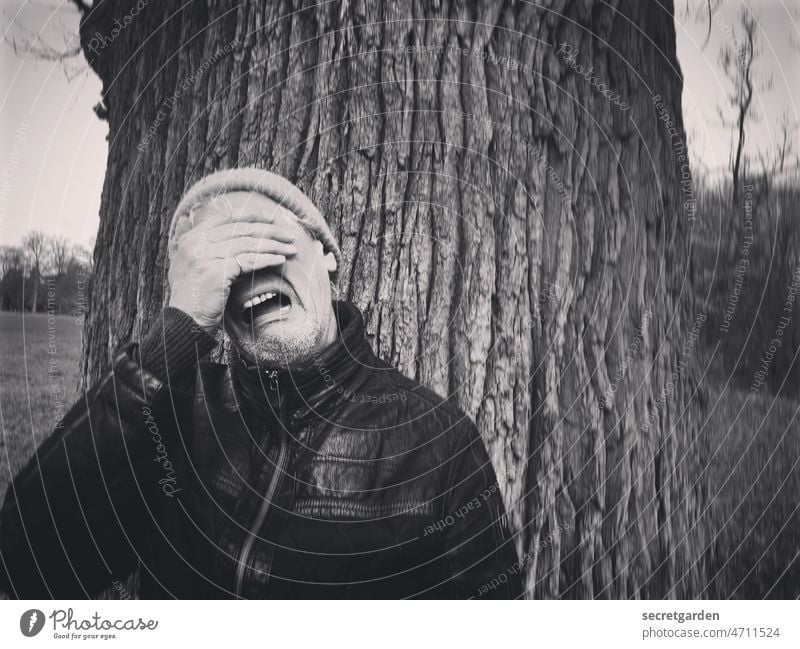 [Clown+Fun-Tour HH2022] Weltschmerz Hide foolish Garden Oak tree Nature Park Structures and shapes Adults Exterior shot Man Human being Tree Winter Cap Cry sad