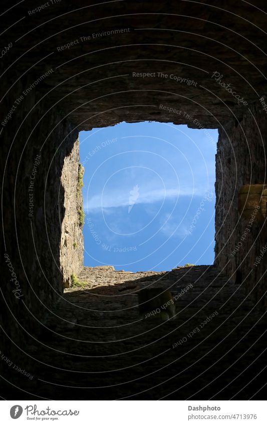 Sky View Through Window in Ancient Castle Wall sky blue blue sky clouds cloudy window opening aperture hole gap wall stone stone wall ancient old wall sunlit
