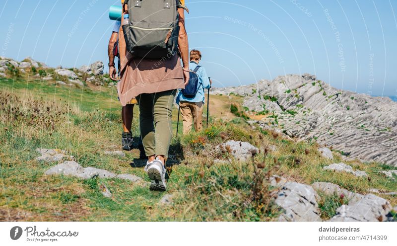 Unrecognizable group of people trekking outdoors unrecognizable back backpack leg foot hiking copy space walk mature nature rock flysch adult family meadow