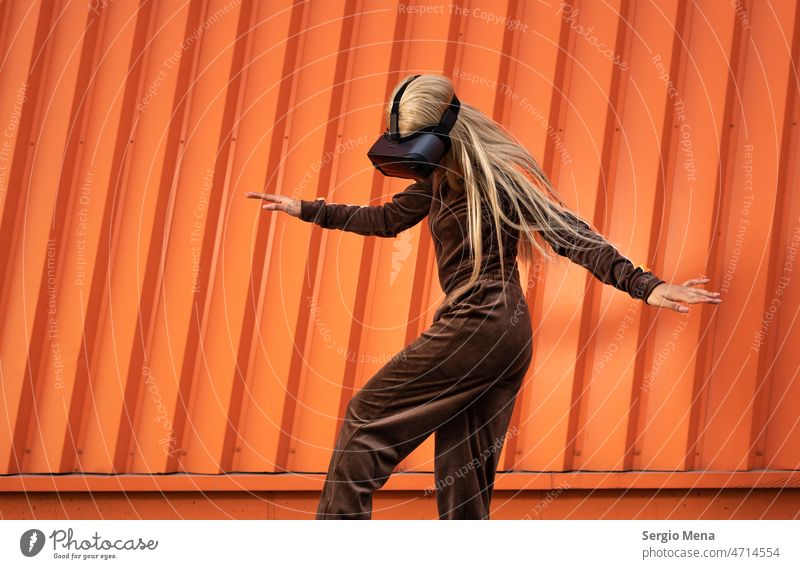 Cheerful African American woman with blonde hair wearing virtual reality goggles on an orange background one person afro american young sportswear lifestyle