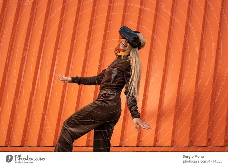 Cheerful African American woman with blonde hair wearing virtual reality goggles on an orange background one person afro american young sportswear lifestyle