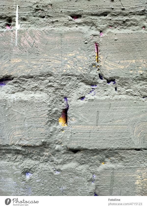 The gray painted wall was certainly once colorful. You can only see that in the joints. Yellow and purple shimmer through there. Wall (barrier) Brick