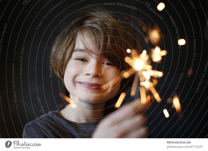Boy with a sparkler smiles into the camera Boy (child) Birthday Sparkler Child Infancy Smiling Happy Positive Happiness contented Face Joy indoors carefree
