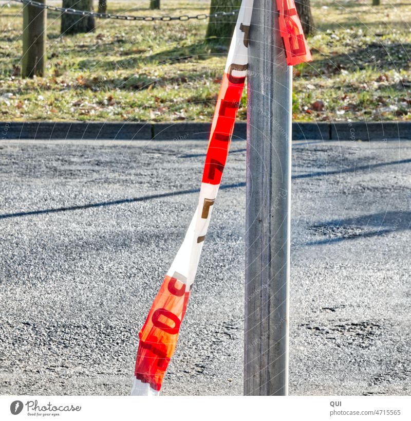 Police barrier tape in front of a stadium event location metal pipe Asphalt red white Writing police Police Force Law enforcers regulate cordon Safety