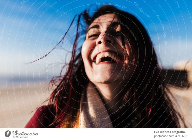 happy woman having fun at the beach on a windy day at sunset. Holidays and fun concept smiling spring blue sky caucasian 30s lifestyles hair laughing happiness
