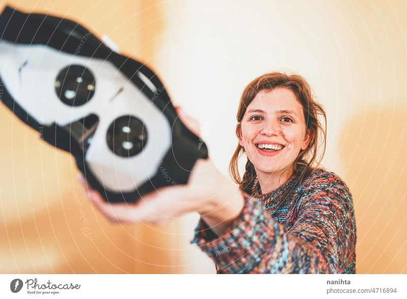 Forced perspective image of a young woman holding the lenses of a vr glasses of cardboard metaverse inside technology sustainability playful gamer weird nerd