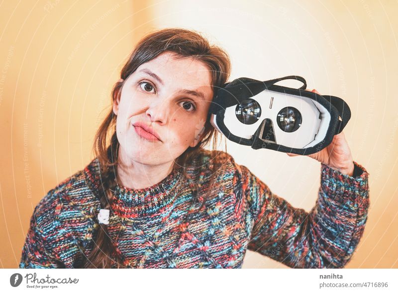 Funny portrait of a young woman holding a cardboard vr glasses metaverse inside lens technology sustainability playful gamer perspective weird nerd nerdy