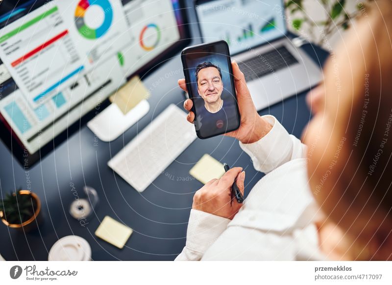 Businesswoman having video chat on mobile phone with her colleague. Businesswoman working with data on charts, graphs and diagrams on computer screen business