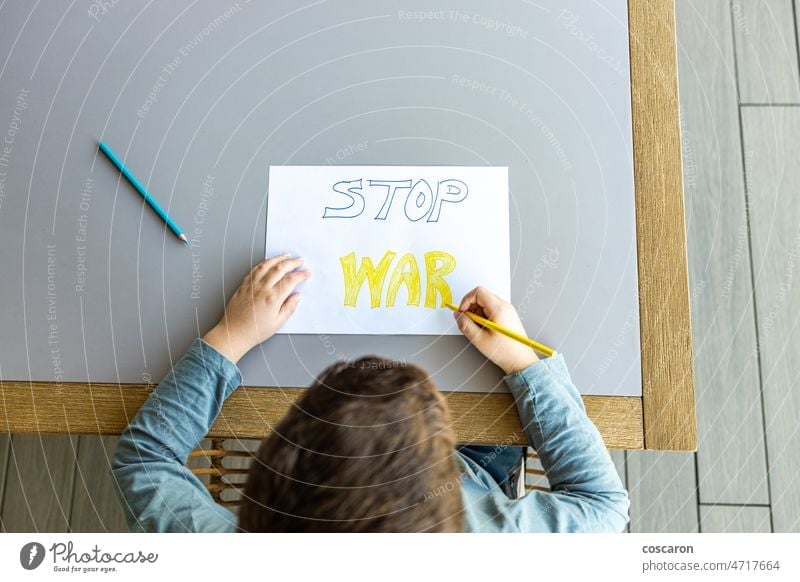 Little kid drawing Stop War on a paper. Ukraine Russia war concept. away from ukraine blue yellow boy child children against war coloring colors conflict fight