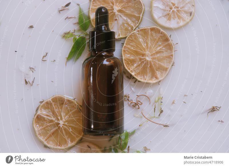 Product photo of a glass dropper bottle containing natural anti aging serum sat against an aromatic milk bath containing dried citrus and herbs glamour fashion