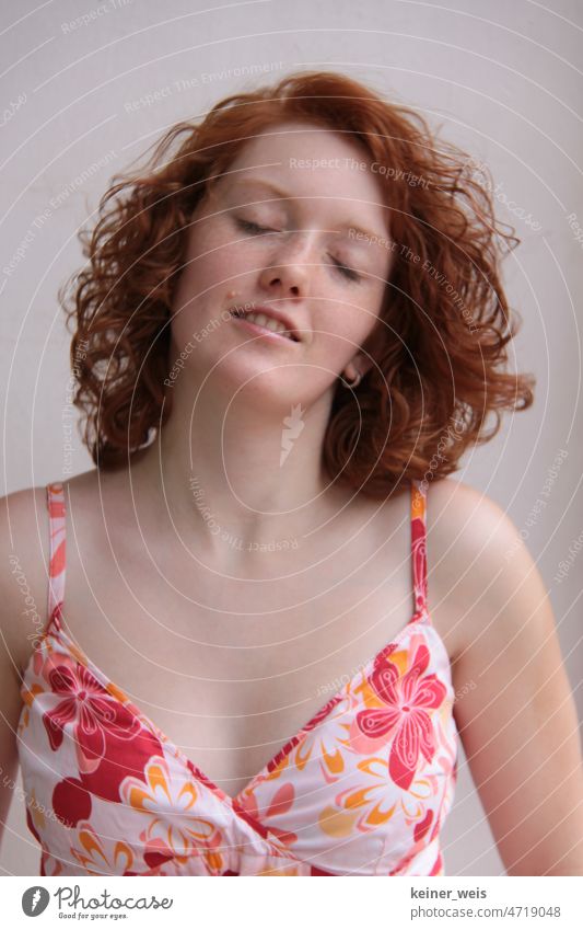 A woman with red curls and closed eyes in summer dress enjoys the sun with a smile Woman Curl curly hair Face Red-haired Freckles Dress décolleté