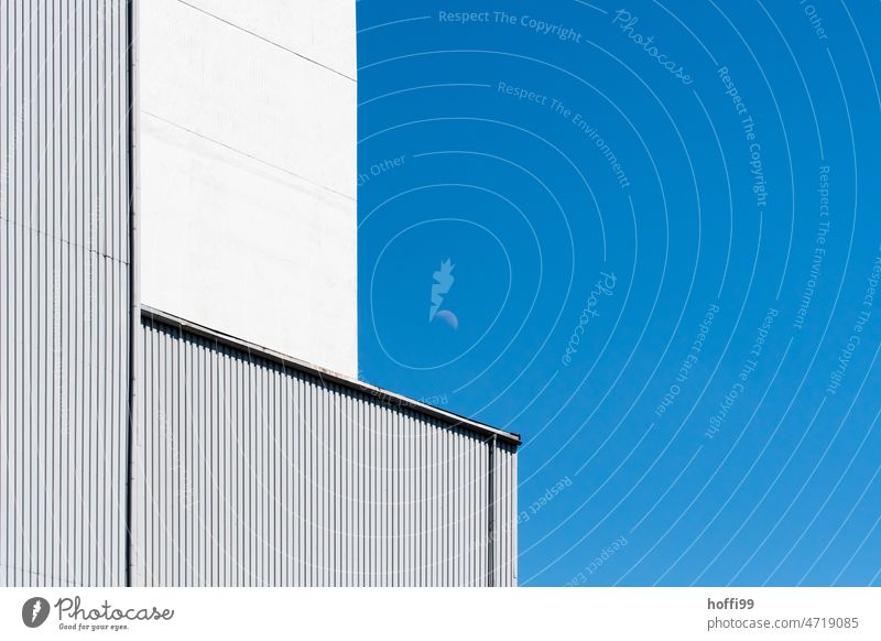 Corrugated metal facade of a warehouse with rising moon Corrugated iron wall Warehouse Moon Industrial plant Blue background Architecture High-rise Modern