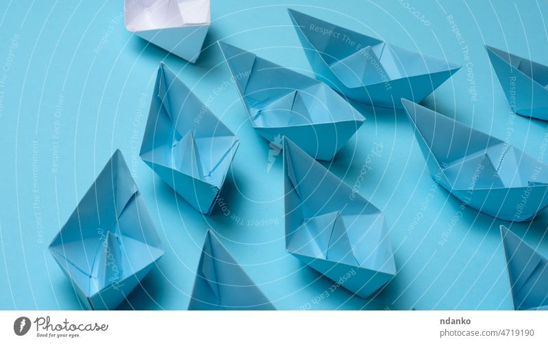 group of blue paper boats follow white against a light blue background. Strong leader concept, mass manipulation. Starting a business with a well-coordinated team, start-up