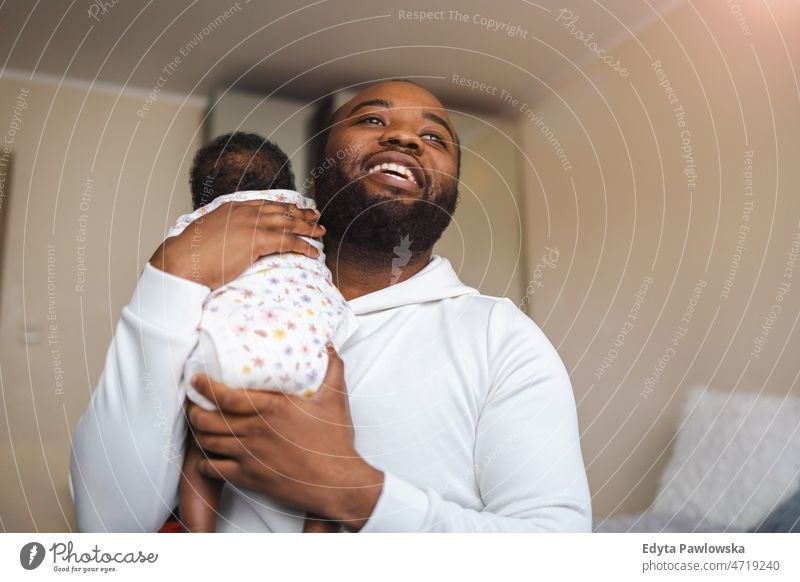 Father holding his baby in arms at home father dad kids child newborn family fatherhood real people indoors house flat apartment enjoy adult authentic black