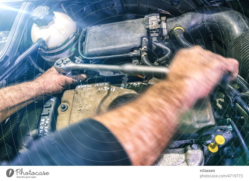 Auto mechanic working on car engine in a mechanics garage. Repair service. authentic close-up shot with motion blur repair auto workshop background
