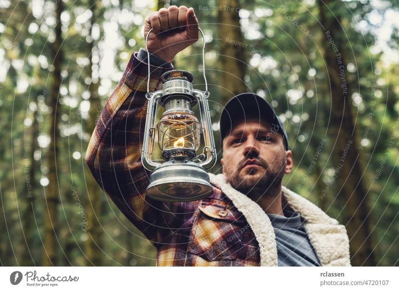 Man hand holding gas lantern in the deep forest gasoline lamp burning candle man discover halloween lost pine darkness hiker adventure arm deep woods nightmare