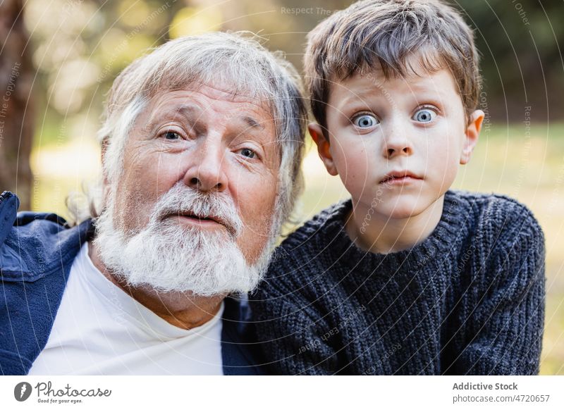 Positive senior grandfather looking at camera and grandson goggle eyes portrait boy man grimace make face positive kid child little male aged elderly appearance
