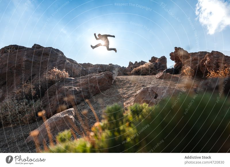 Man jumping above rocks at sunlight in highland man tourist stone explore discovery freedom travel wanderlust male nature traveler wild environment boulder