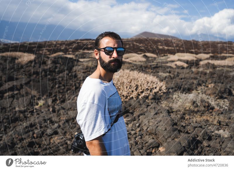 Bearded man standing in volcanic valley during trip tourist vacation tourism photo camera adventure desert explore male serious nature destination environment