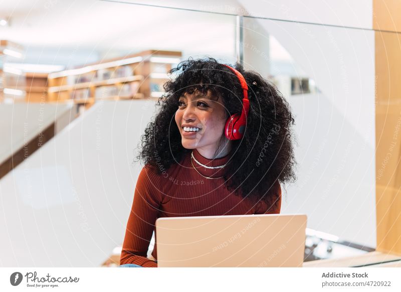 Glad African American female listened to music from laptop woman library using meloman student headphones smile browsing education enjoy ethnic happy