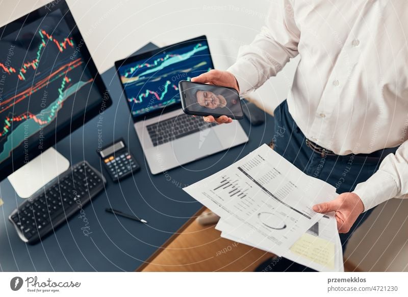 Businessman trading stocks online. Stock investor discussing numbers at graphs while video conversation with his colleague. Business team planning and analyzing stock market graphs. Business man investing stock online