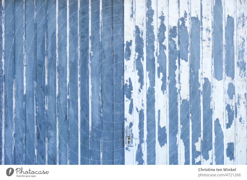 An old weathered garage door. The blue and white paint is flaking off artfully. Garage door Wood Weathered Old Colour Blue White Flake off Unkempt symmetric