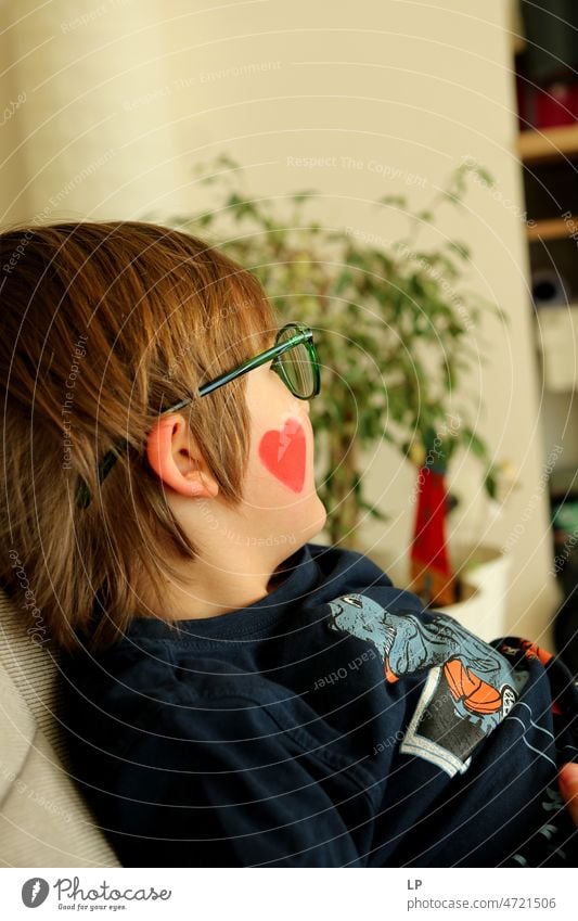 child wearing glasses looking away with a heart painted on his face Emotions Mysterious Identity Uniqueness Smiling face laughing child fortunate joyfully