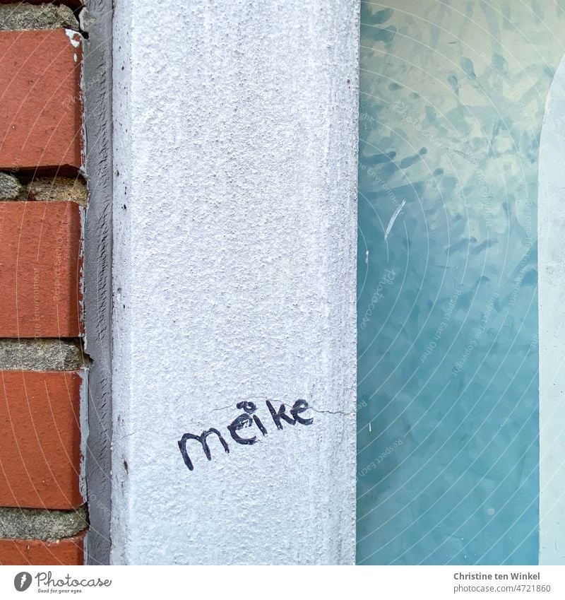 The first name "meike" is written on the white concrete pillar between the red clinker wall and the light blue wall woman's name Name writing Word words Written