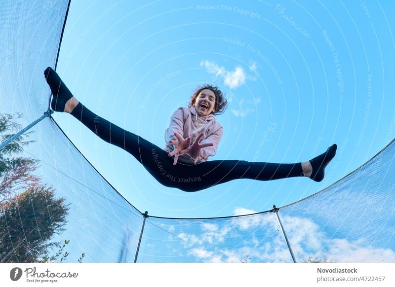 Portrait of a happy 13 year old girl jumping on a trampoline portrait teenage 13 - 18 years teenager alone isolated outdoors active high young lifestyle