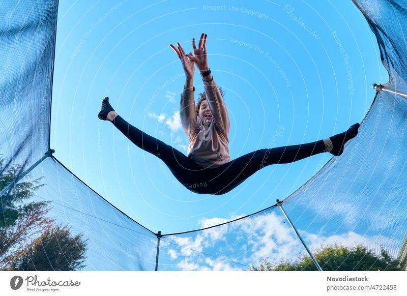 Portrait of a 13 year old girl jumping on a trampoline young female 13 - 18 years teenager active sport lifestyle outdoos portrait legs legs up person caucasian