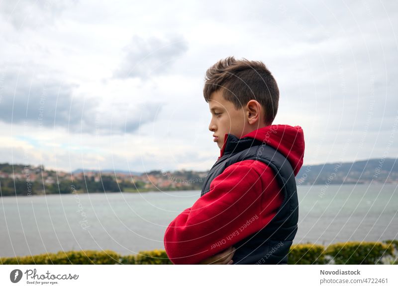 Portrait of a 9 year old boy outside, looking angry and upset, sea on the background, profile picture portrait Profile outdoors child kid alone isolated person