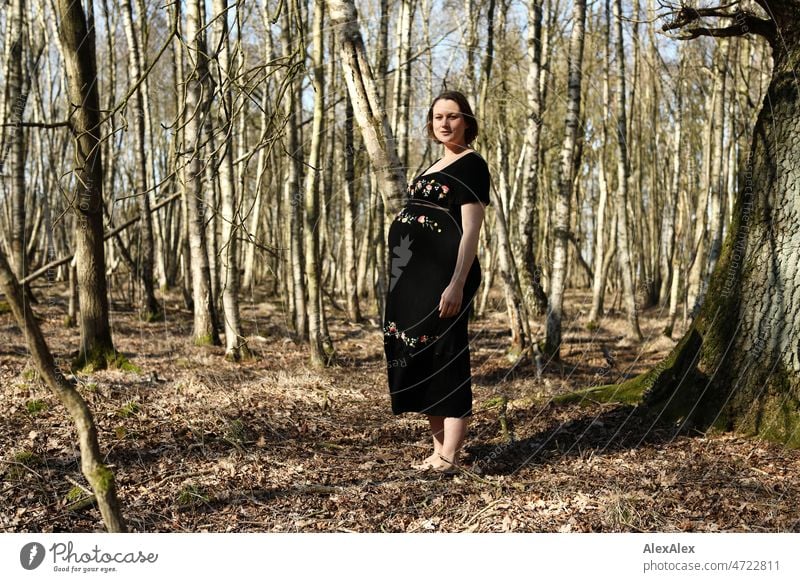 Young pregnant woman standing barefoot in forest in black maternity dress Young woman Woman pretty Beauty & Beauty Pregnant new life Life Dress Barefoot