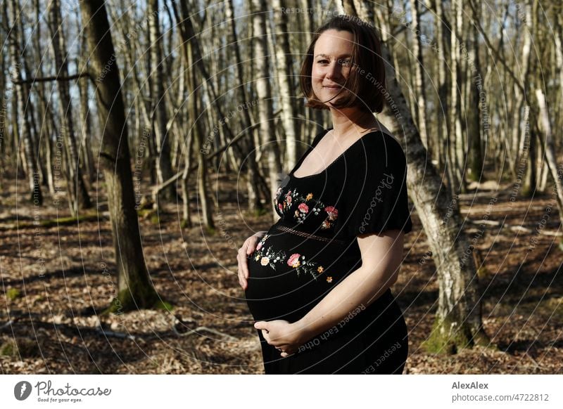Young pregnant woman standing in forest in black maternity dress Young woman Woman pretty Beauty & Beauty Pregnant new life Life Dress Barefoot Pregnancy photo